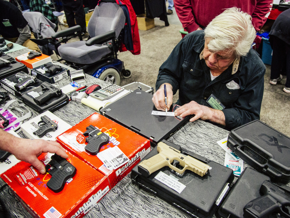 Jim Jones fills out a tag for a recently purchased handgun, while a customer fills out background check materials. Whitney Hayward/Staff Photographer