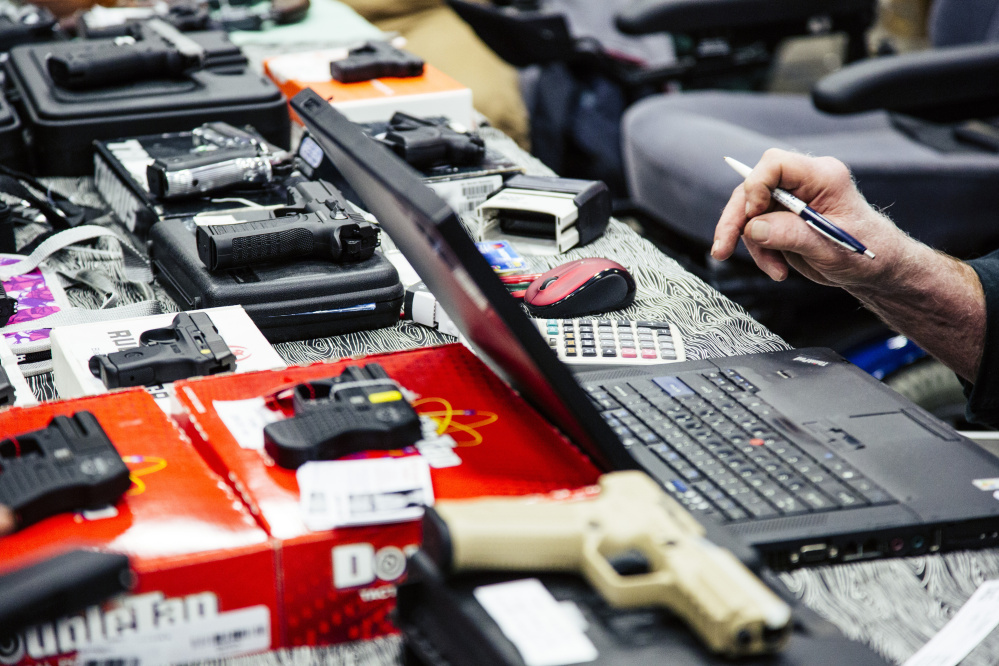 Jim Jones does some pricing calculations while a customer fills out their background check materials before purchasing a handgun at the gun show at the Augusta Civic Center in Augusta on Saturday. Whitney Hayward/Staff Photographer)