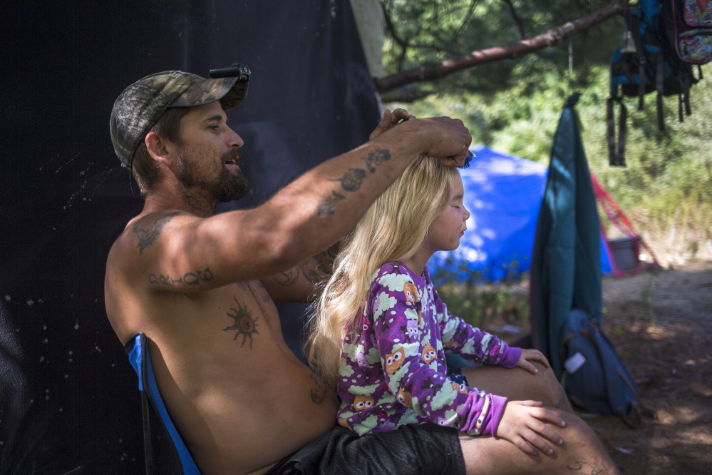 Troy brushes Arianna's hair to put it up in a bun at their campsite. Troy says that Arianna likes when he does her hair because he doesn't pull on it as much as her mom.