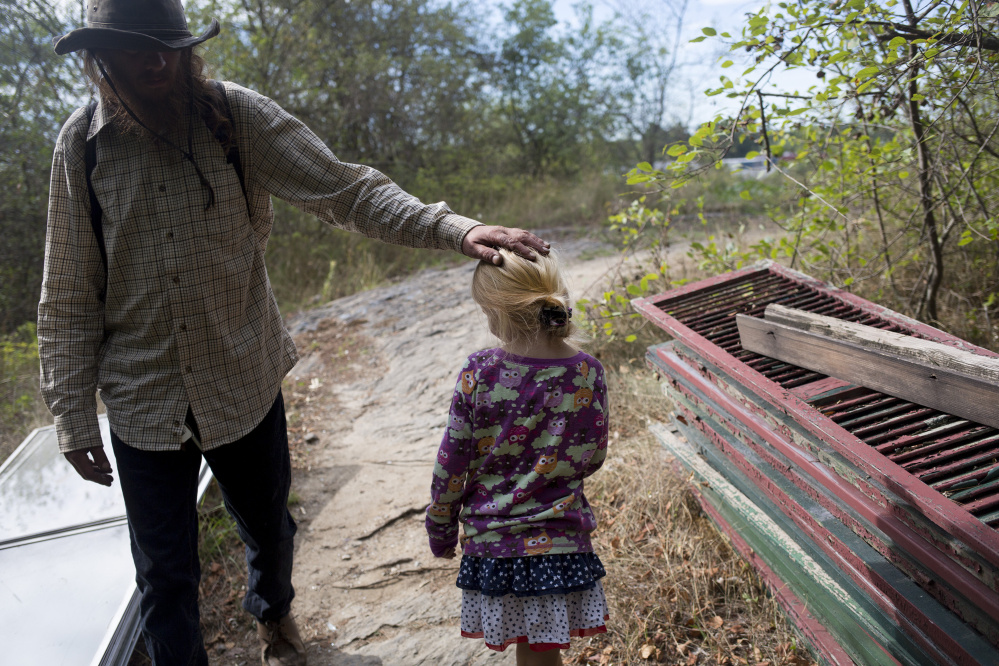 Matt Coffey, who has lived at the Portland encampment known as Tent City for five years, pats Arianna on the head as he walks by her. Many of the other people living at the encampment grew fond of the bubbly little girl.