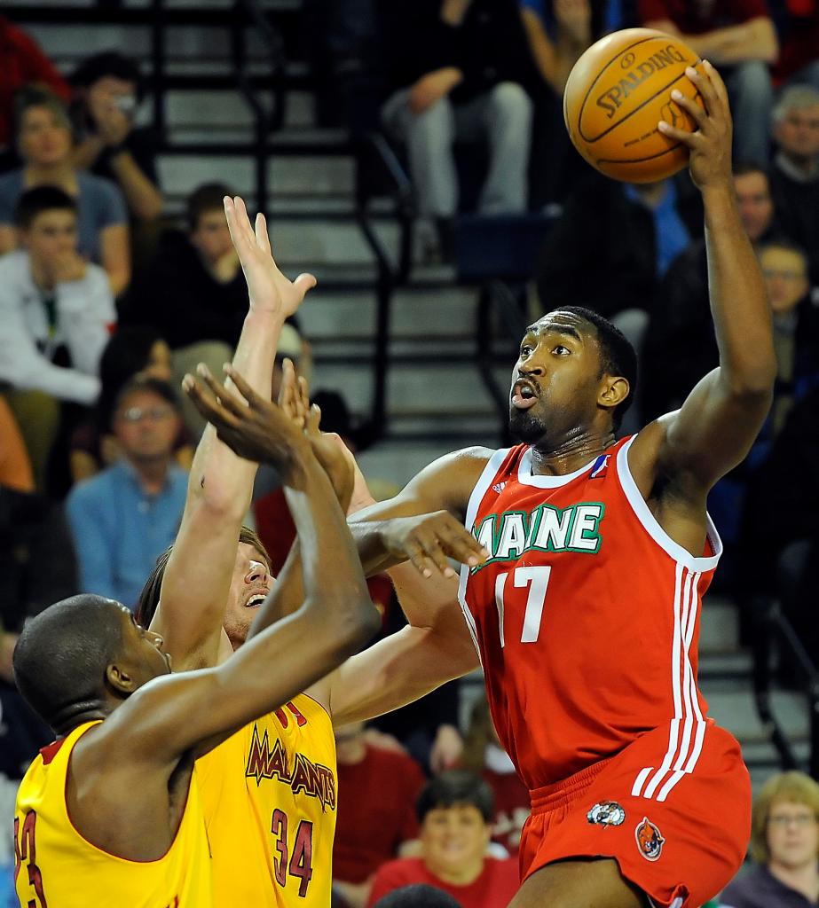 Darnell Lazare of the Red Claws makes a strong move to the basket against Anthony Kent, left, and Sean Sonderleiter during Wednesday night’s game at the Portland Expo. The Mad Ants beat Maine for the third straight time.