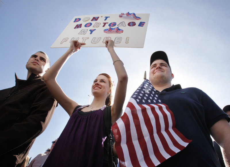 Three Mainers – Corey Thompson of Spruce Head, left, and Rebecca Harper and Jacob Harper, both of Cushing – listen to speakers at the rally Wednesday.