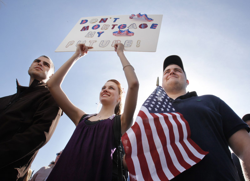 Corey Thompson of Spruce Head, Rebecca Harper of Cushing and Jacob Harper of Cushing listen to speakers at the Tea Party rally.