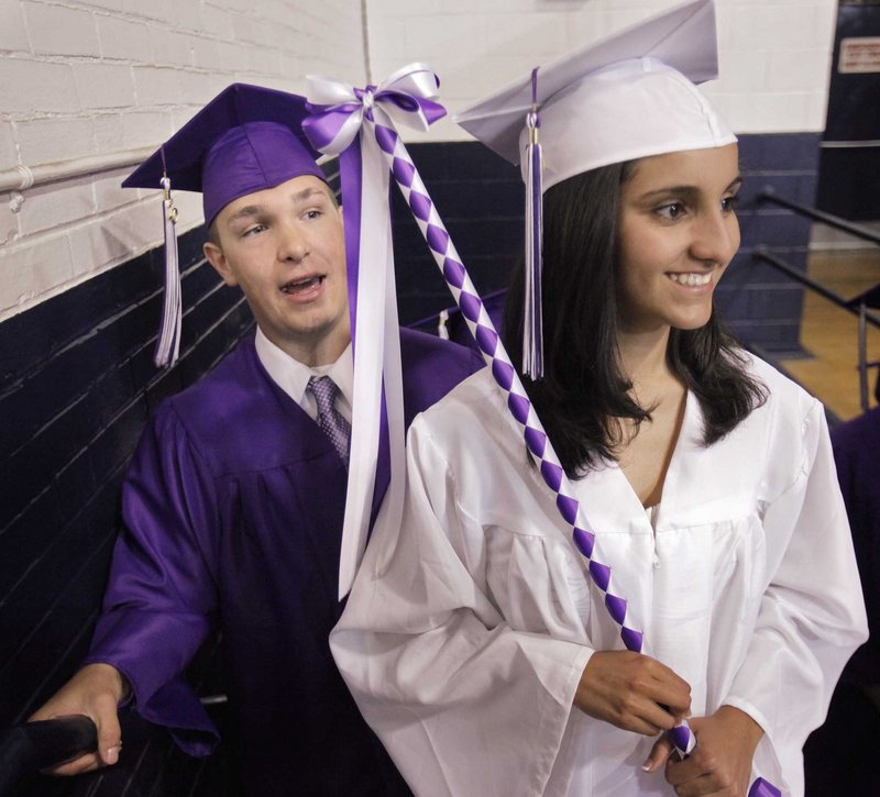 Deering High School seniors Matt Caiazzo, left, and Mohdis Delijani wait to enter the Portland Expo for Deering’s graduation ceremony.