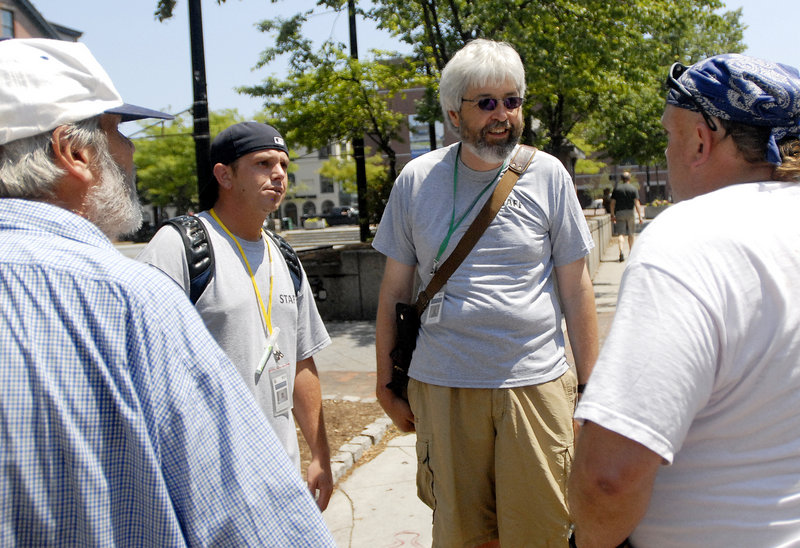 Jesse Flynn, background left, and outreach partner John Dana, members of Portland's Homeless Outreach & Mobile Engagement Team, speak with two men at Congress Square Plaza during their walk through the city Wednesday. Team members say they serve two groups of clients: homeless people and local business owners.