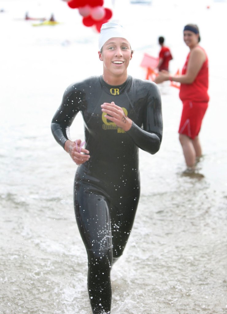 Kristen Desrosiers of Gorham is all smiles as she emerges from the water as the first female finisher in the 2.4-mile swim from Peaks Island across Casco Bay.