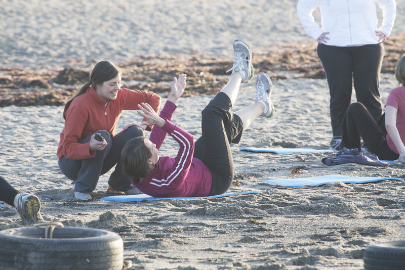 Amber Bell (left) critiques a participant in a Biddeford Saco Boot Camp session at Biddeford Pool. Bell offers the workouts three times per week, rain or shine, for workout warriors who enjoy a physical challenge, accountability and camaraderie.