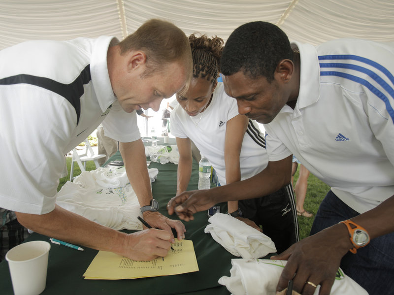 Dave Weatherbie, left, works with the husband-and-wife running team of Ayelech Assefa, center, and Dejene Berhanu after a press conference Friday leading to the running of the TD Bank Beach to Beacon 10K today in Cape Elizabeth.