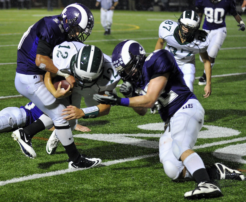 Renaldo Lowry, left, tries to strip the ball away from Bonny Eagle quarterback Matt Rollins as Devon Fitzgerald also closes in during the first half Thursday night.