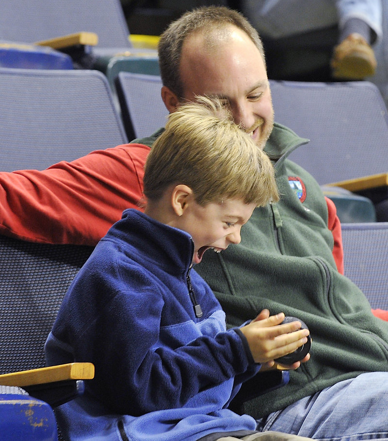 Keji Wiessner, 6, rejoices after his father, Greg, handed him a puck that flipped over the glass at the Civic Center on Monday. Only 2,621 fans turned out for the holiday afternoon game.