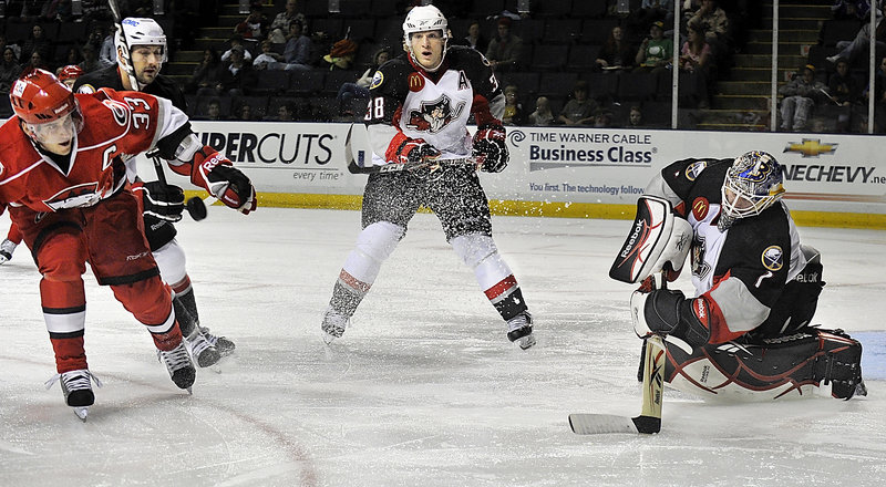 Bryan Rodney of the Checkers, left, reaches for a puck cleared by Portland goalie Jhonas Enroth as Pirates Colin Stuart, second from left, and Tim Conboy look on Monday afternoon.