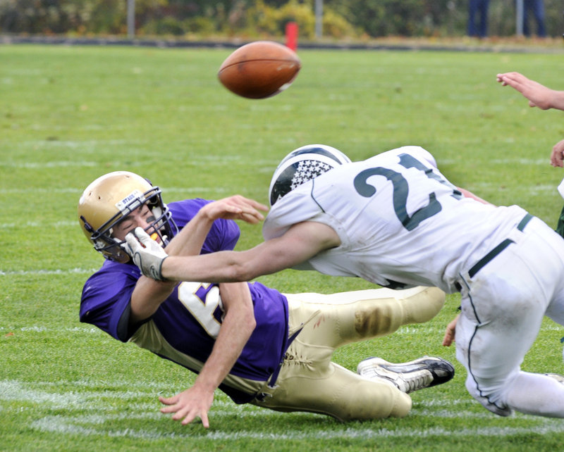 Peter Gwilym of Cheverus gets the ball off just in time to complete a pass Saturday while being taken down by Nick Adkins of Bonny Eagle during Cheverus’ 23-20 victory at home.