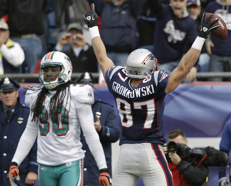 Rob Gronkowski celebrates his touchdown catch as Miami safety Chris Clemons walks off the field in Sunday's game at Foxborough, Mass. The Patriots ended the regular season with a 38-7 win.