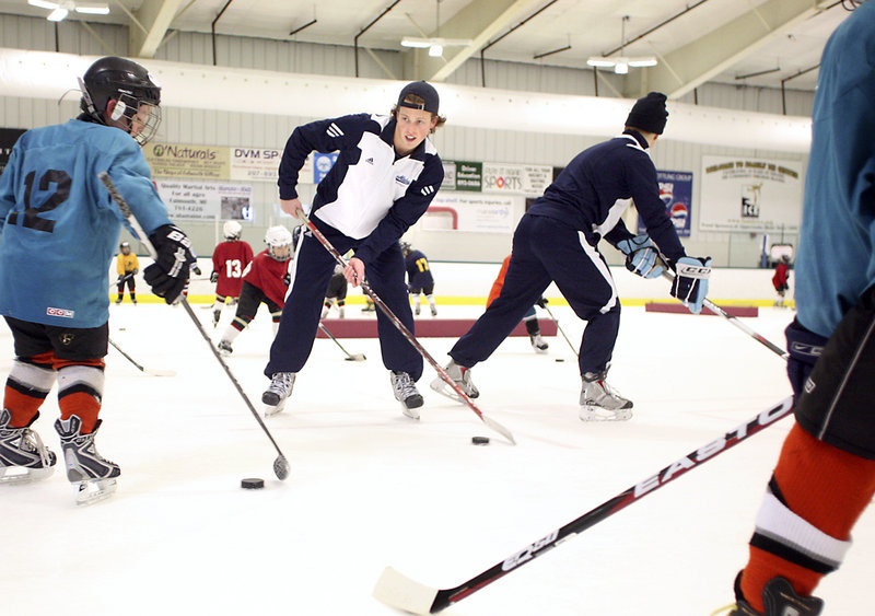 Nick Pryor, a sophomore at the University of Maine, demonstrates the proper way to control the puck to youngsters at Family Ice in Falmouth.