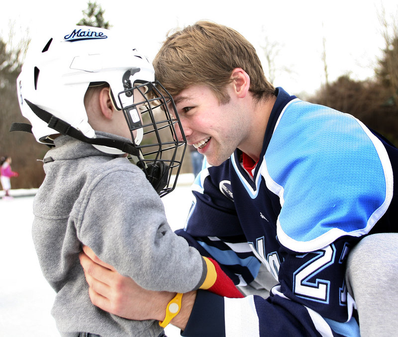 Will O'Neill of the University of Maine gives an embrace and a head butt to Kieran MacDonald of Levant during a youth public skate Saturday at Family Ice in Falmouth. The Black Bears will meet the U.S. under-18 national team today at the Cumberland County Civic Center.