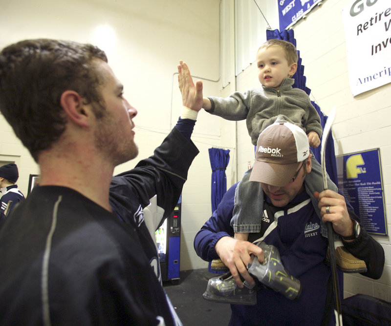 Kieran MacDonald, 2, of Levant exchanges a high-five with University of Maine sophomore Joey Diamond.