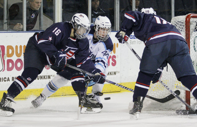 Maine's Ryan Hegarty, center, jousts with Zac Larraza, left, and Cole Bardreau of the U.S. U-18 junior national team during their exhibition Sunday at the Cumberland County Civic Center. Maine pulled away for a 5-1 win.