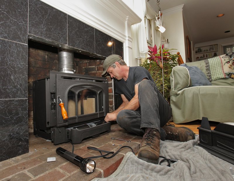 Craig McCausland installs a wood-burning fireplace insert at a Falmouth condo in the fall of 2009. A federal tax credit cut the cost of the improvement by 30 percent.