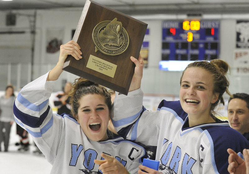 York captains Mackinnon Hill, left, and Hannah Keating raise the trophy the Wildcats won Wednesday for defeating Biddeford 4-1 in the Western Maine final in girls' hockey at the Portland Ice Arena. York will play in the state final for the first time Saturday, against St. Dominic at Lewiston.