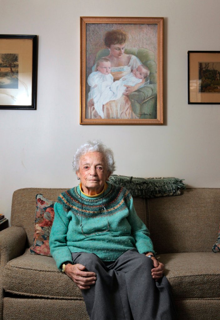 Nancy Payne of Falmouth poses below a portrait that she painted of her mother holding her and her twin sister, Penelope Dwinell. “I am compulsively creative,” she said.