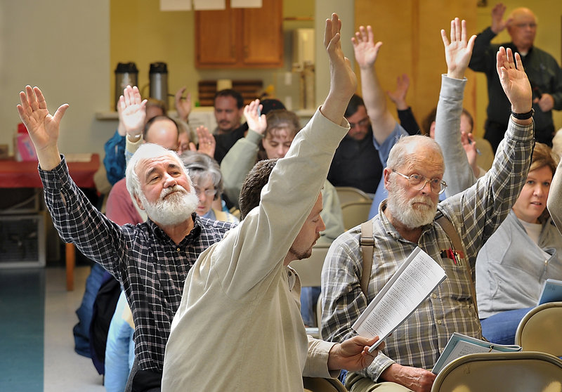 Max Brandt, left, makes sure his vote is seen by the moderator as he votes on one of many issues on the agenda with the rest of the residents attending the Limington Town Meeting, including Cory Abbott, front, and George Bouchard, right.