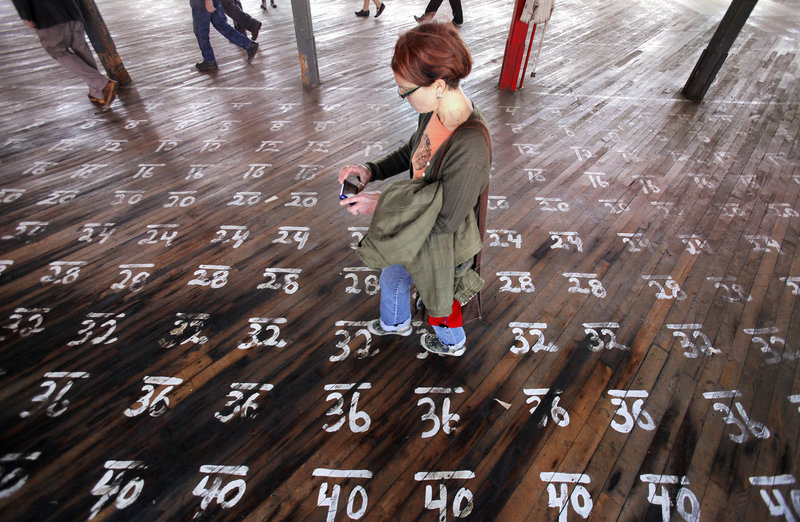 Laura Dunn takes a picture Thursday of numbers on the floor of a storage area at a mill in Biddeford formerly owned by WestPoint Stevens.