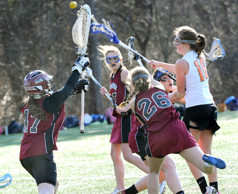 Katie Cawley, right, of North Yarmouth Academy reaches over the defense and sends a shot past Freeport goalie Molly Lane for a goal Thursday during a girls' lacrosse season opener at Yarmouth. NYA, the defending Class B champion, took a 10-1 halftime lead on the way to a 14-4 victory.