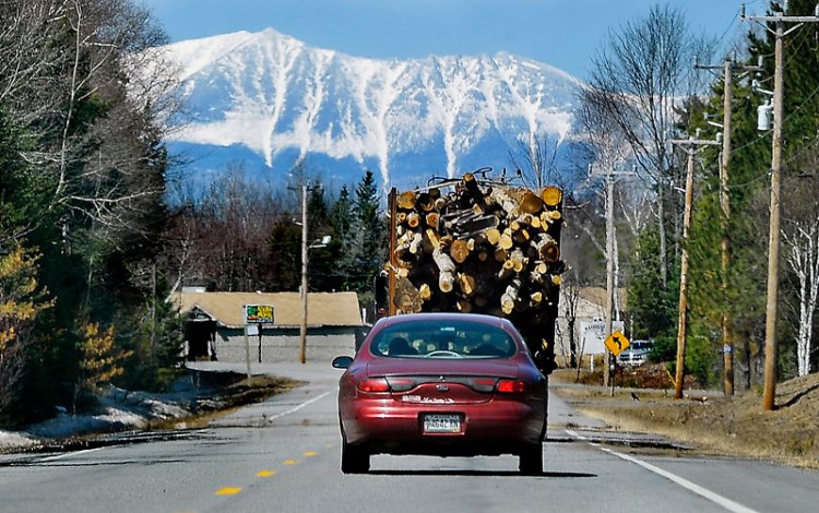 Mount Katahdin looms in the distance as a truck carries logs to a logging yard in Millinocket in 2014. On Saturday, close to 1,000 runners are expected for an unusual road race that aims to help the struggling mill town.