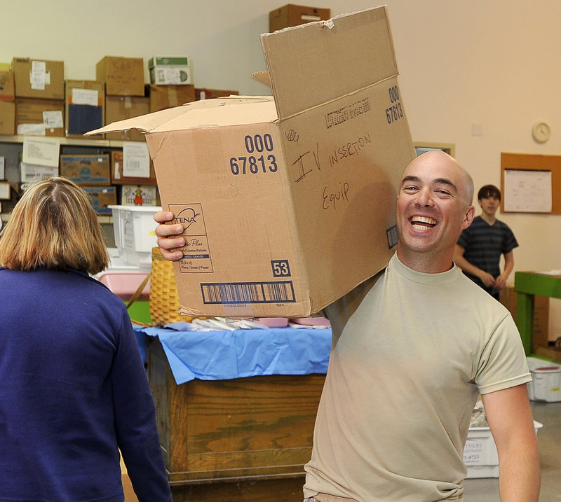 Cpl. Zachary Cole of the 716 Engineer Battalion of the U.S. Army Reserves carries a loaded box of medical supplies to a truck in Scarborough.