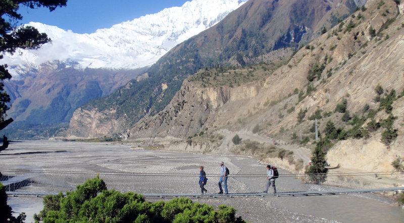 Trekkers cross a swinging bridge over a river in Nepal, home to eight of the 10 highest mountains in the world.