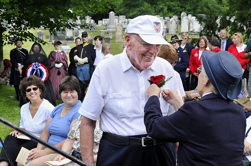 Dick Johnson, great-grandson of Civil War Pvt. William Johnson of Saco and finder of his gravesite, receives a red rose boutonniere from Alfreda Thurston, president of the American Legion Auxiliary of Yarmouth, during a headstone dedication service at the Old Baptist Cemetery in Yarmouth on Saturday. At left are Jacqueline Wing and Colleen Verrill, great-great-grandaughters of Pvt. Johnson.