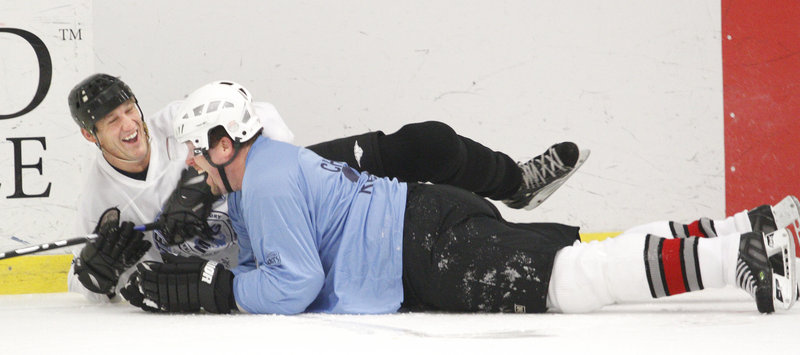 Portland Junior Pirates coach and former UMaine player Trevor Roenick, facing, and fellow Junior Pirate coach and former Pirates player Brad Church share a laugh after tripping each other during a charity hockey game Sunday at MHG Ice Centre in Saco.