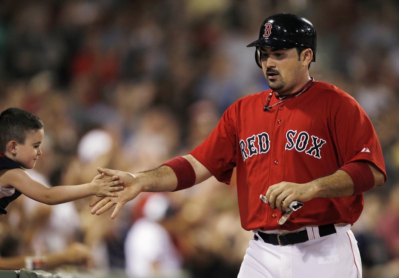 Adrian Gonzalez is congratulated by a young fan Friday night after scoring in the seventh inning against Seattle at Fenway Park. Boston broke open a one-run game with five runs in the seventh to hand the Mariners a 13th straight loss.