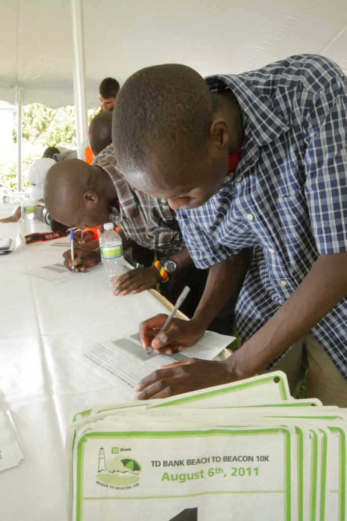 Allan Kiprono of Kenya, who placed second in the Beach to Beacon last year in his American road racing debut, fills out his registration forms with another Kenyan, Lani Rutto.