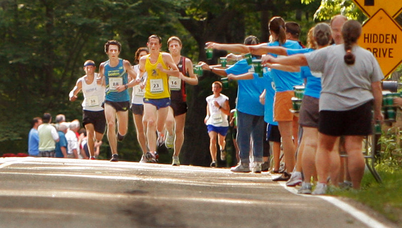 Volunteers hold out water to runners along Shore Road in Cape Elizabeth during the TD Bank Beach to Beacon 10K Saturday. To some runners, finishing fast is important. To others, just finishing makes them proud. "I learned to power up the hills so I can let gravity take me down the other side," said Mark Gillis, 53, of South Portland.