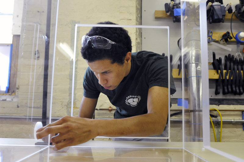 Matthew Laforest joins pieces of a base tank before gluing them together at Marine Ecological Habitats in Biddeford.