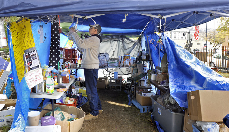 Alan Porter, 45, of Portland helps to move an Occupy Maine tent to another area of Lincoln Park in Portland on Monday after a chemical bomb was tossed into the camp Sunday.