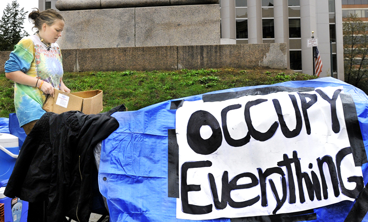 Demi Colby, 23, of Portland, one of a handful of demonstrators gathered in Monument Square this morning as part of a nationwide protest against Wall Street, cleans up after the protesters were ordered by Portland police to take down their tents.