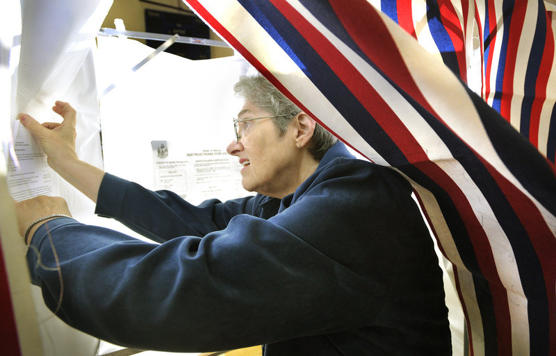 Voting registrar Betsy Jo Whitcomb tapes instructions and other notices inside voting booths Monday at Falmouth High School. Falmouth and the rest of Cumberland County will vote today on a $33 million bond issue for civic center repairs.