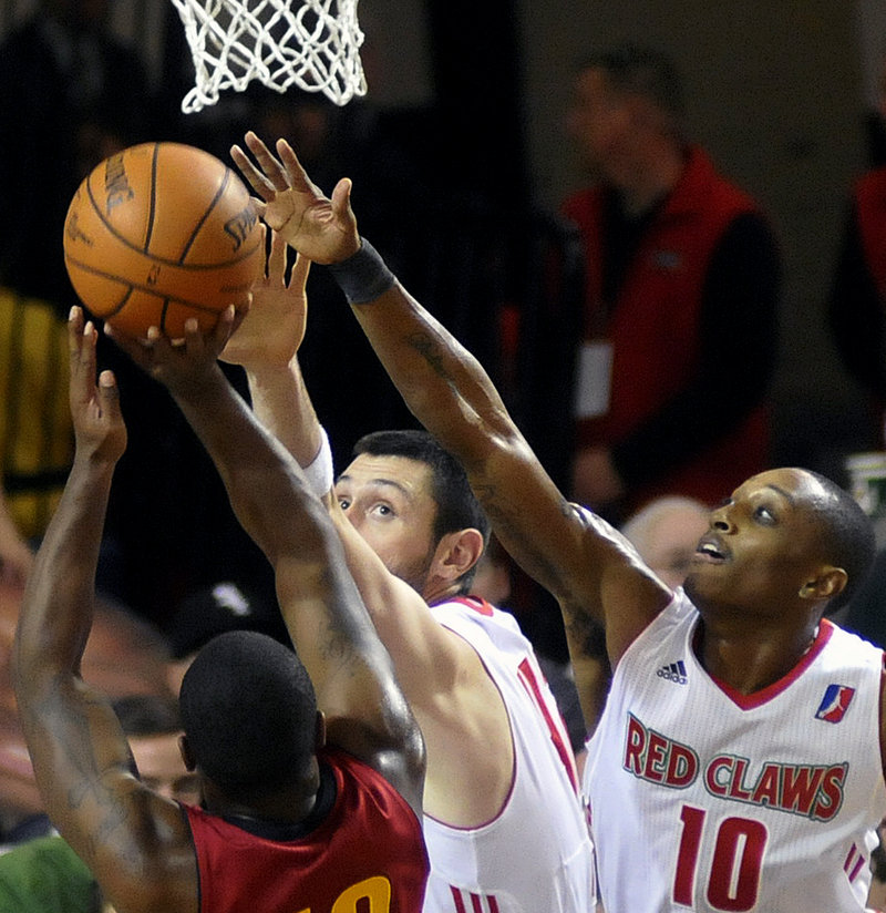 Mike Tisdale, center, and Kenny Hayes attempt to block Tory Jackson's shot in Sunday's game at Portland. The Red Claws rallied for a 99-91 win.