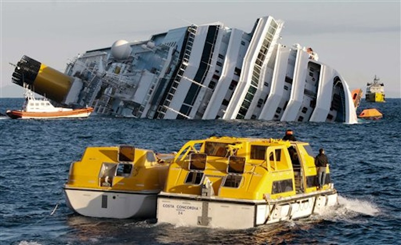 Investigators on Sunday approach the luxury cruise ship Costa Concordia which leans on its starboard side after running aground in Italy. (AP Photo/Gregorio Borgia)