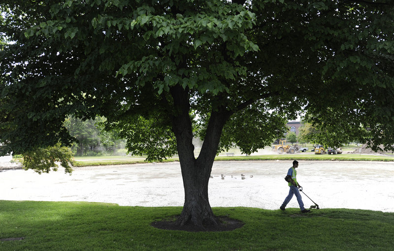 Dan Feeney of South Portland Parks and Recreation trims grass on Monday at Mill Creek Park along the pond, which has been drained during construction to improve the 10-acre city park.