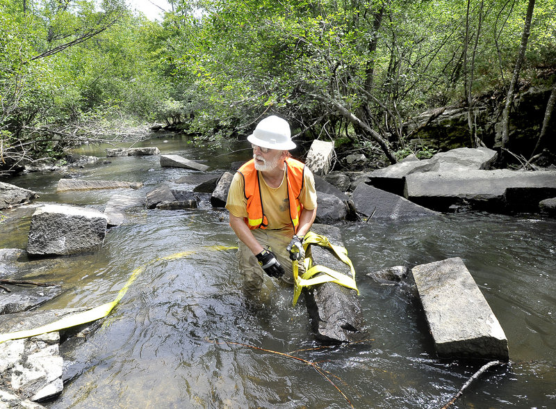 Steven Koenig, executive director of Project Share, secures a strap around a granite block as local, state and federal partnering agencies begin a three-day fish-passage restoration project in the Royal River in Yarmouth on Tuesday.