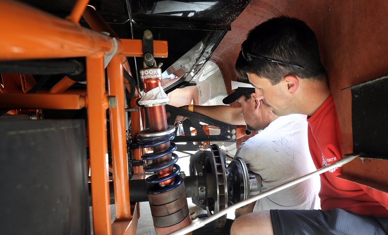 Bob Emery, left, and Aaron Ricker work on the suspension of Jason Ricker’s race car in the pits at Beech Ridge Motor Speedway in Scarborough.