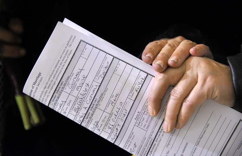 The women's hands touch over their "Intentions of Marriage" form outside the Office of the City Clerk in Portland. Donna Galluzzo and Lisa Gorney were among 15 couples to seek licenses and about a half-dozen to wed early Saturday.