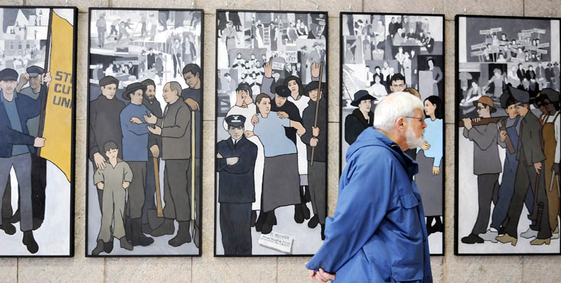 Ken Jones, of Farmingdale, on Monday examines the labor mural that is now hanging on the wall of the Cultural Building's atrium in Augusta, which serves as the entryway to the Maine State Museum.