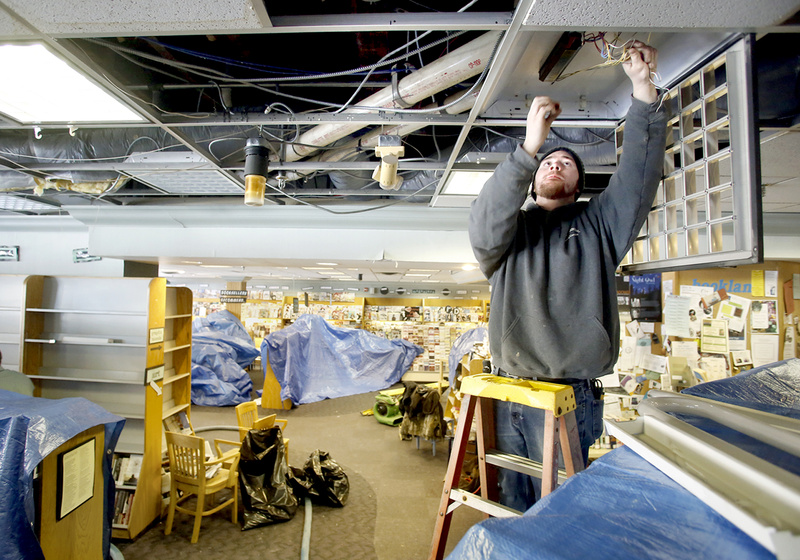 Tony Napolitano of T.A. Napolitano Inc. disconnects the lights Sunday at Longfellow Books in Portland, which were damaged from water after a second-floor sprinkler pipe froze and burst Saturday night during the blizzard.