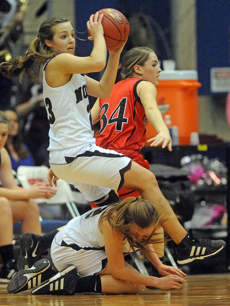 Kelsie Richards of Nokomis looks to pass Wednesday while tripping over teammate Taylor Shaw. Defending for Camden Hills is Megan LeGage. Nokomis won, 45-40.