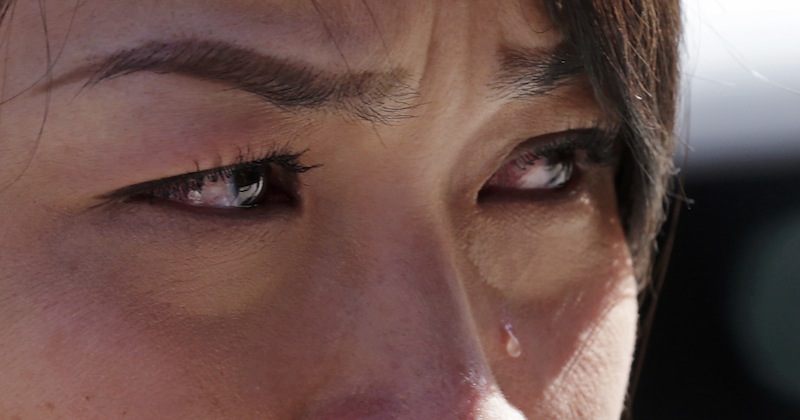 Boston Marathon runner Vu Trang, of San Francisco, cries at a makeshift memorial on Boylston Street near the finish line of Monday's Boston Marathon explosions, which killed at least three and injured more than 140, in Boston, Wednesday, April 17, 2013. The bombs that blew up seconds apart near the finish line left the streets spattered with blood and glass, and gaping questions of who chose to attack at the Boston Marathon and why. (AP Photo/Charles Krupa)