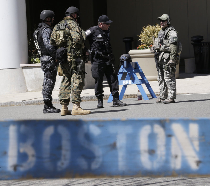 Officials in tactical gear stand guard behind a Boston Police Department barricade near the site of the Boston Marathon explosions, Wednesday, April 17, 2013, in Boston. The city continues to cope following Monday's explosions near the finish line of the marathon. Authorities investigating the deadly bombings have recovered a piece of circuit board that they believe was part of one of the explosive devices, and also found the lid of a pressure cooker that apparently was catapulted onto the roof of a nearby building, an official said Wednesday. (AP Photo/Julio Cortez)